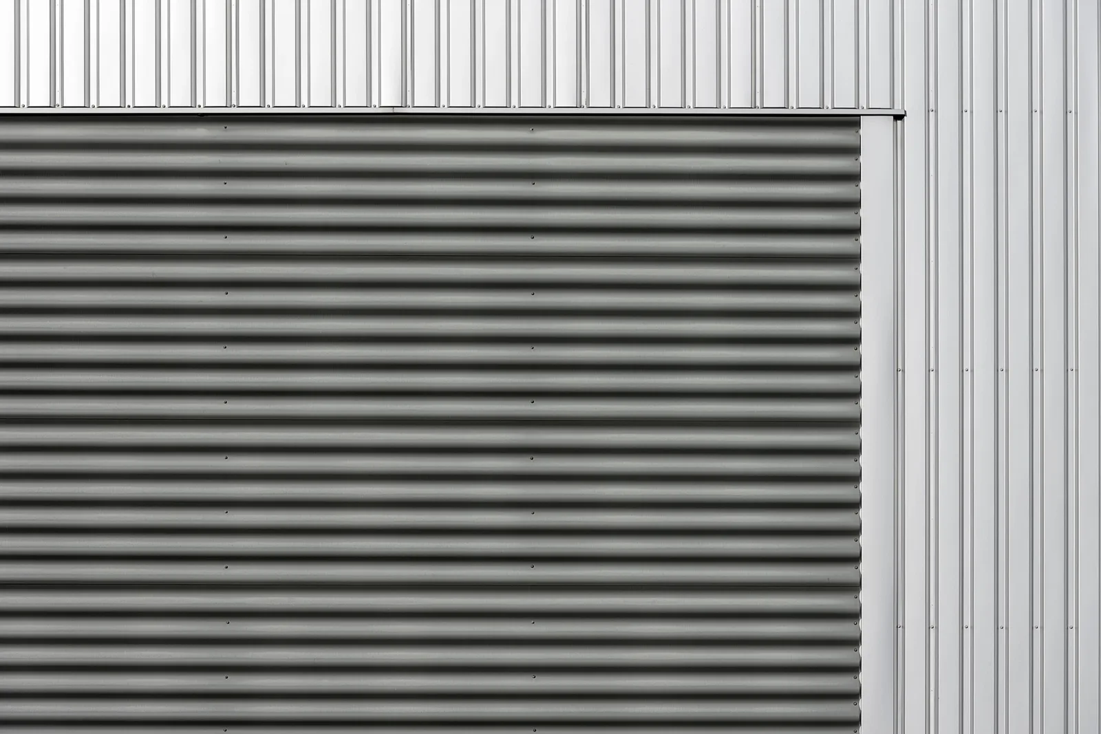 Plan rapproché d'un portail en aluminium blanc RAL 9006 sous lumière naturelle, finition métallisée satinée.